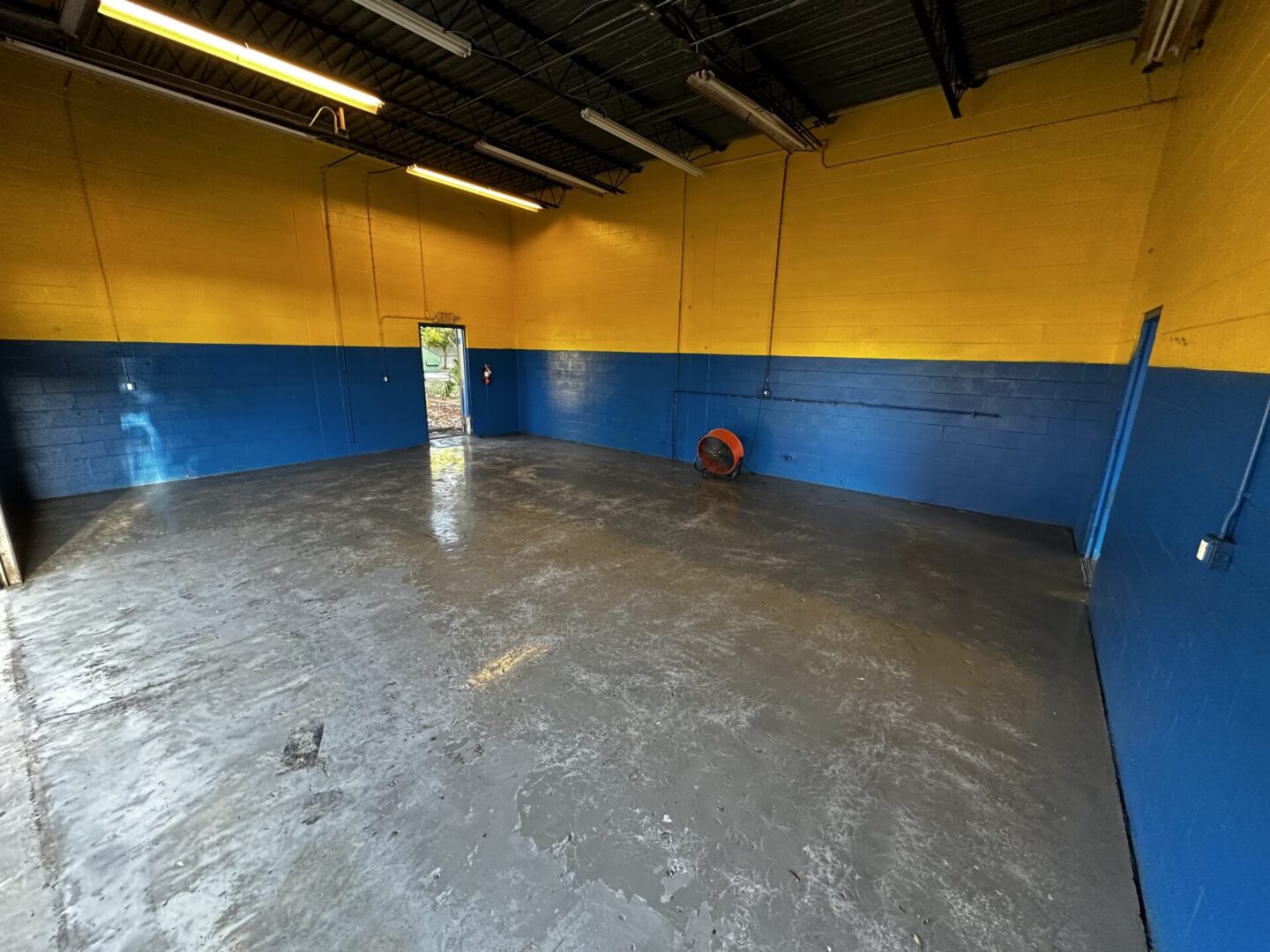 A room with blue and yellow walls and concrete floors.