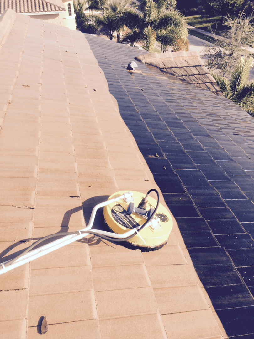 A tile roof being cleaned by a power washer.