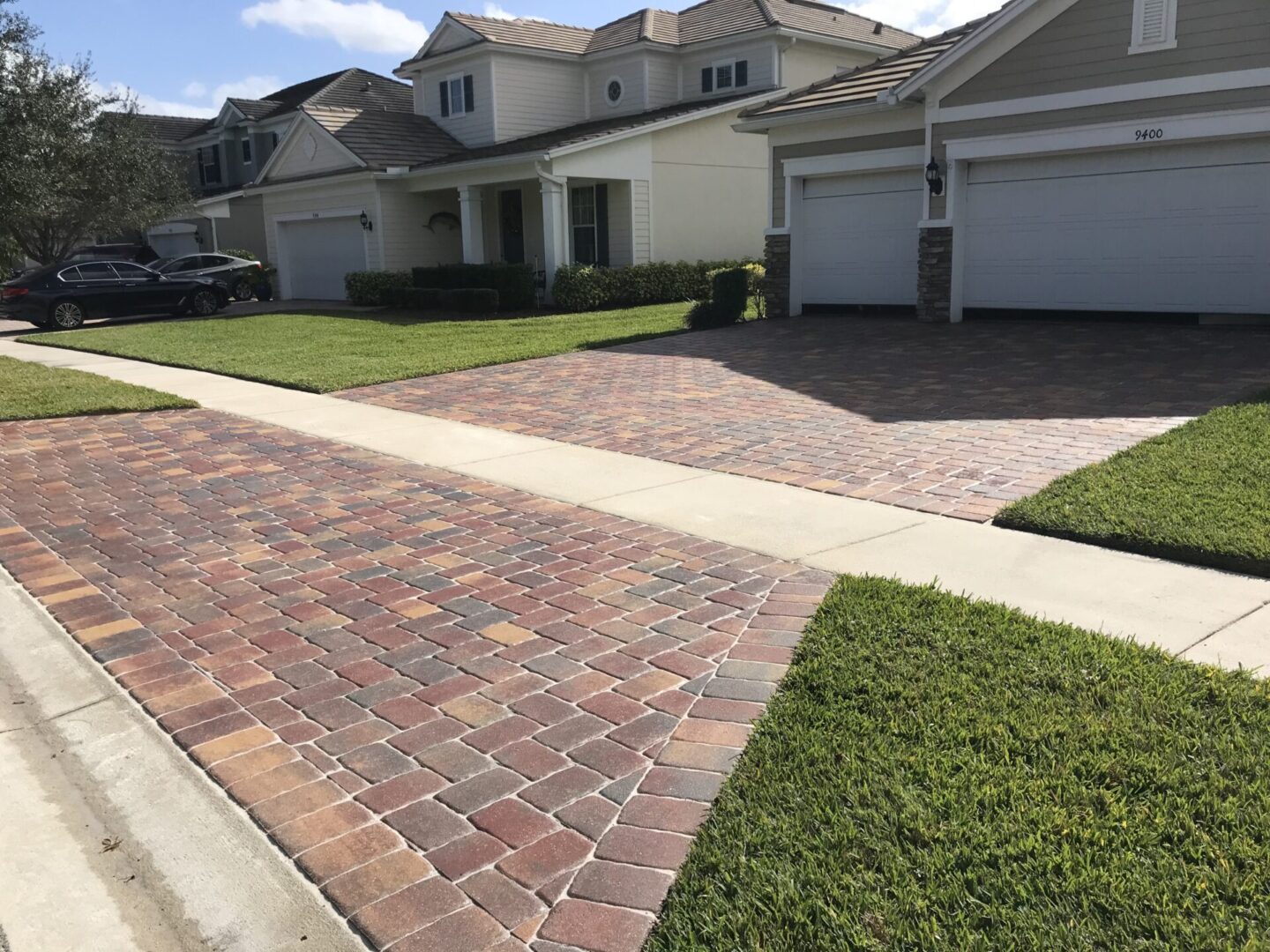 A driveway with brick and grass in the middle of it.
